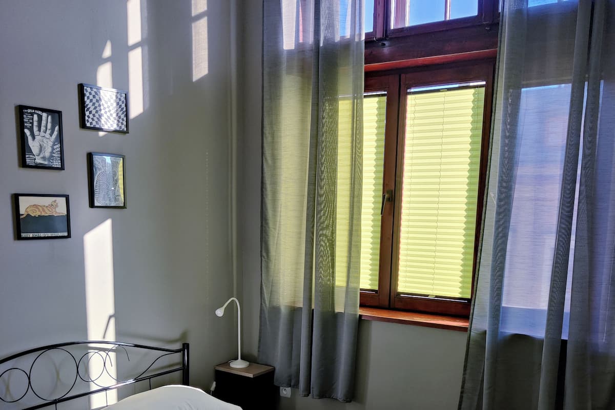 A hotel room with a bed, a nightstand, a lamp, and a window with curtains.