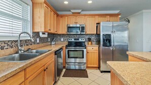 A modern kitchen with wooden cabinets, stainless steel appliances, and a tiled backsplash.