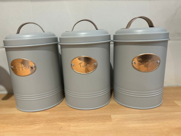 Three grey storage containers with handles and metal labels on a wooden surface. - Balham Double Deluxe Room 3 (London)