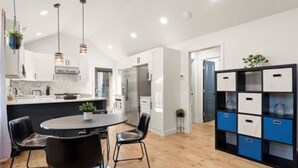 A modern kitchen with a central island, black chairs, and pendant lighting. - NEW Decatur Bungalow - World Cup Ready Ready (Candler-McAfee)