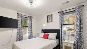 A bedroom with a bed, bedside table, lamp, and curtains. - NEW Decatur Bungalow - World Cup Ready Ready (Candler-McAfee)