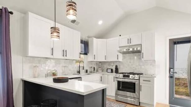 A modern kitchen with white cabinets, a central island, stainless steel appliances, and pendant lighting. - NEW Decatur Bungalow - World Cup Ready Ready (Candler-McAfee)