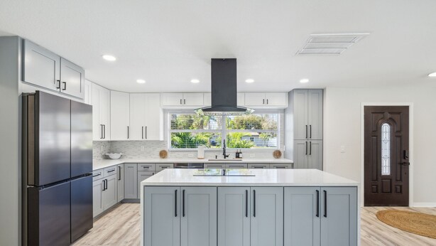 A modern kitchen with a large island, stainless steel appliances, and light gray cabinetry. - Coastal Comfort Getaway in the Heart of SRQ (Sarasota)