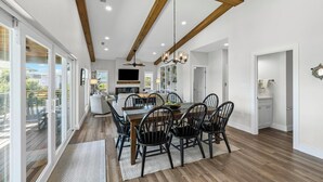 Un vaste espace dédié à la salle à manger, avec une table et des chaises en bois, un lustre et un ventilateur de plafond.