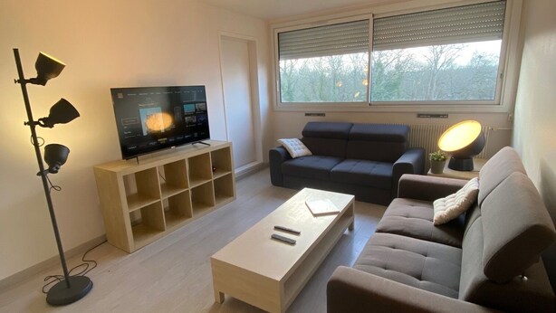 A modern living room with a flat-screen TV, a sofa, a coffee table, and a floor lamp.