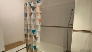 A bathroom with a shower, a glass-enclosed sink, and a patterned shower curtain.