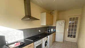 A compact kitchen with a stove, oven, washing machine, and refrigerator.
