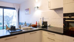 Una cocina moderna con encimera negra, armarios blancos, horno integrado y ventana con vistas al exterior.