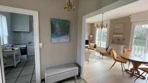 Uma cozinha moderna com armários brancos e uma área de jantar com mesa e cadeiras redondas.
