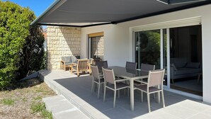 En terrasse med bord og stole, en stenvæg og et overdækket område.