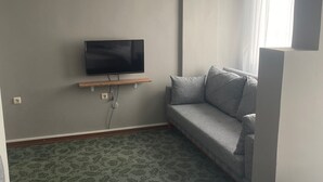 Une chambre d’hôtel avec un lit, un canapé, une télévision et une moquette à motifs.