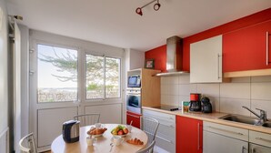 A kitchen with a dining table, chairs, a coffee maker, and a view of the outdoors.