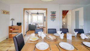 A dining area with a wooden table set for six, chairs, and a buffet table with bread.