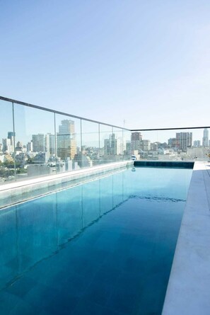 Una piscina en la azotea con vista al horizonte urbano.