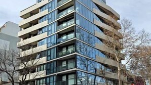Un immeuble moderne à plusieurs étages, doté d’une façade en verre et d’un toit plat.