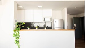 Une cuisine moderne avec des armoires blanches, un réfrigérateur en acier inoxydable et un plan de travail en bois.