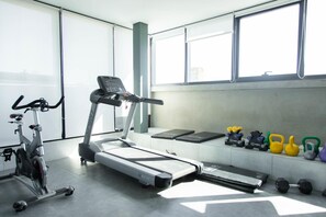 Une salle de sport équipée d’un tapis de course, d’un vélo d’appartement et de divers poids.