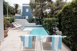 A swimming pool with lounge chairs and potted plants. - De Waterkant House (Cape Town)