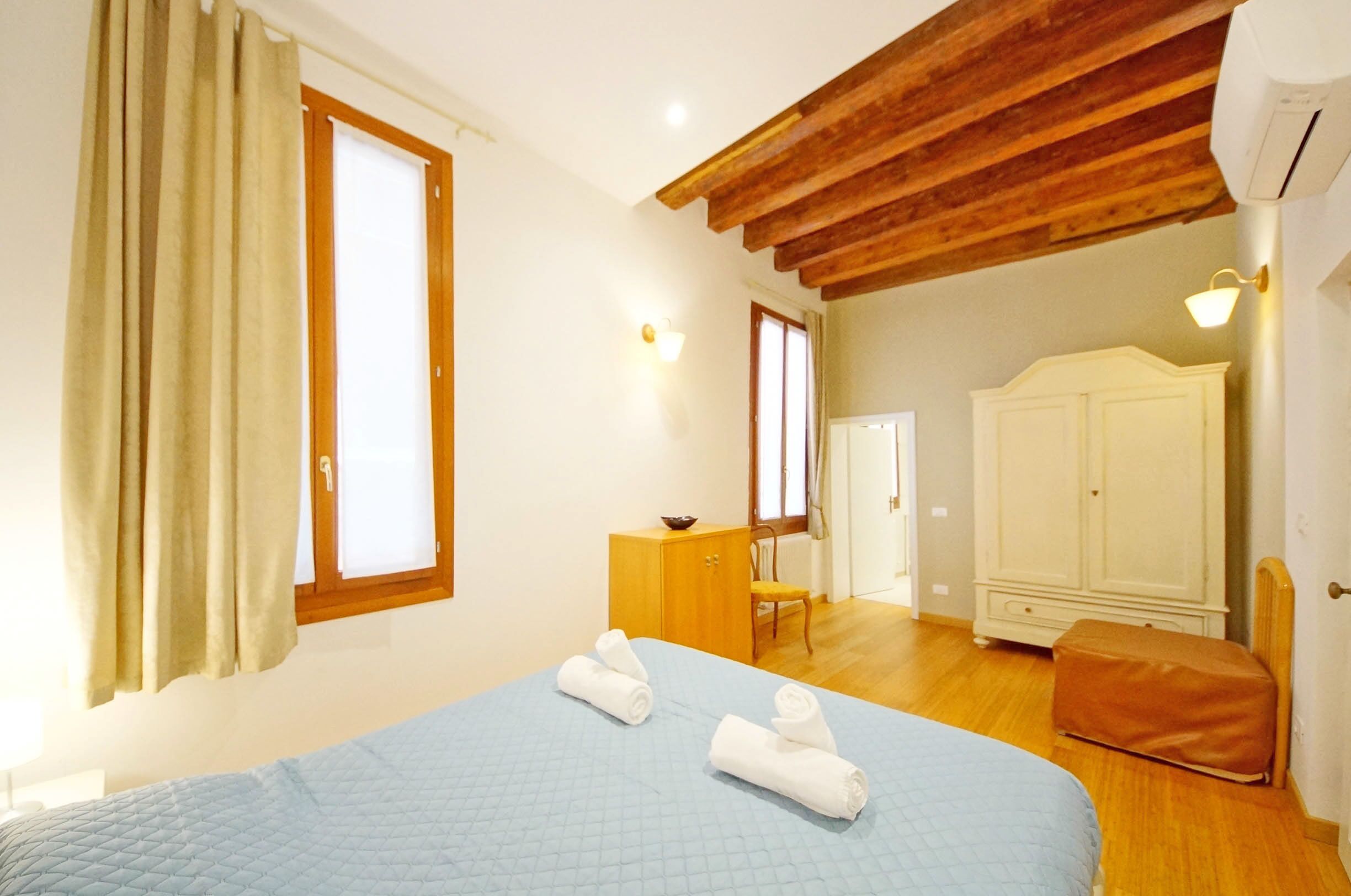 Une chambre à coucher avec un lit, une armoire en bois, un bureau et une chaise.