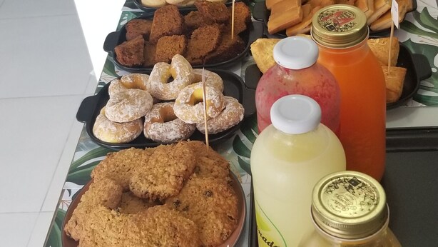 Uma mesa de buffet com diversos produtos de panificação, incluindo biscoitos, doces e pão, juntamente com várias garrafas de bebidas.