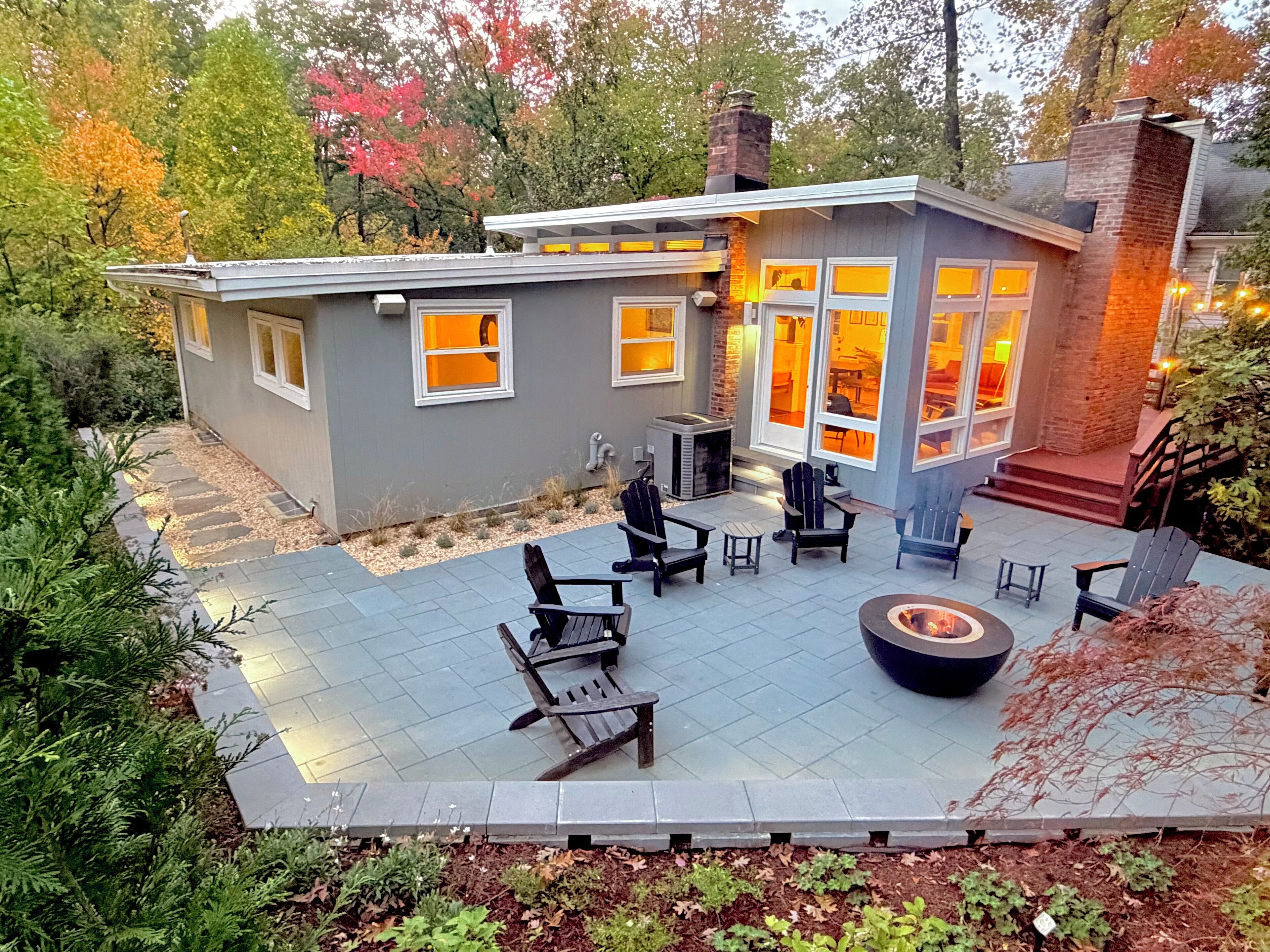 Een modern huis met een patio, buitenmeubilair en een vuurkuil.
