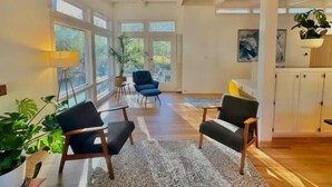 A spacious living room with large windows, a modern chair, a small table, and a potted plant. - Best Vacation Home in Arlington, 4 bedrooms 3 full bath, 8 beds, 12 guests (Arlington)
