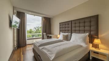 A modern hotel room with a large bed, a desk, and a TV mounted on the wall.