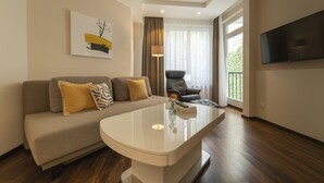 Una sala de estar moderna con un sofá, una mesa de centro, un televisor y una ventana con cortinas.