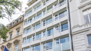 Un edificio de varios pisos con fachada moderna, ventanas amplias y acceso principal a nivel de calle.