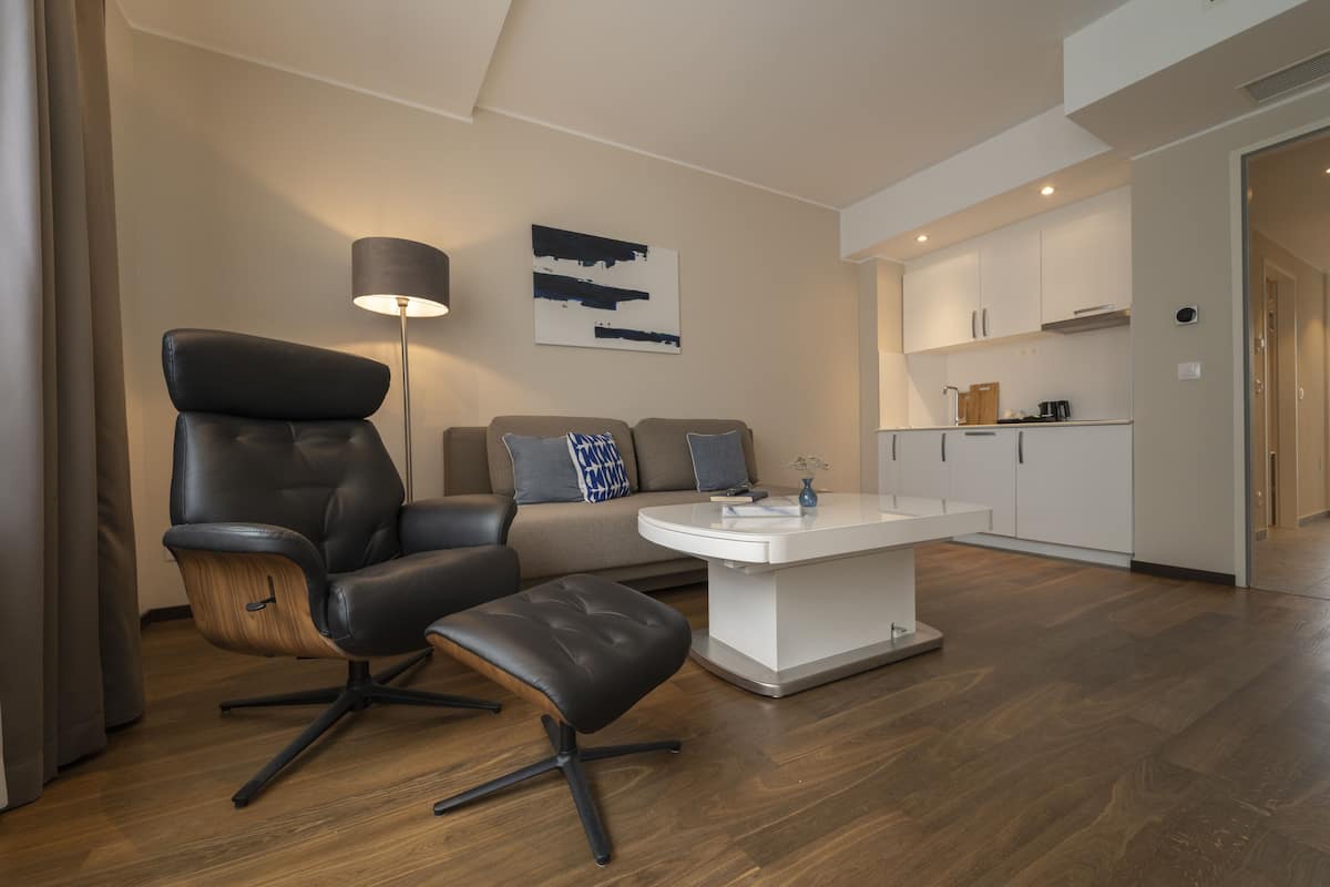 A modern living room with a leather chair, a wooden coffee table, and a sofa with cushions.