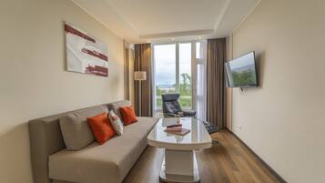 Una habitación de hotel moderna con sofá, una mesa de centro, televisor y vistas al exterior.