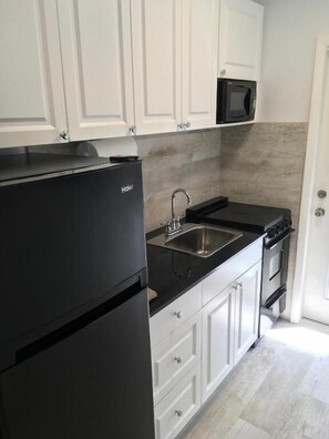 Een koelkast met diepvriezer, een microgolfoven, een oven, een kookplaat