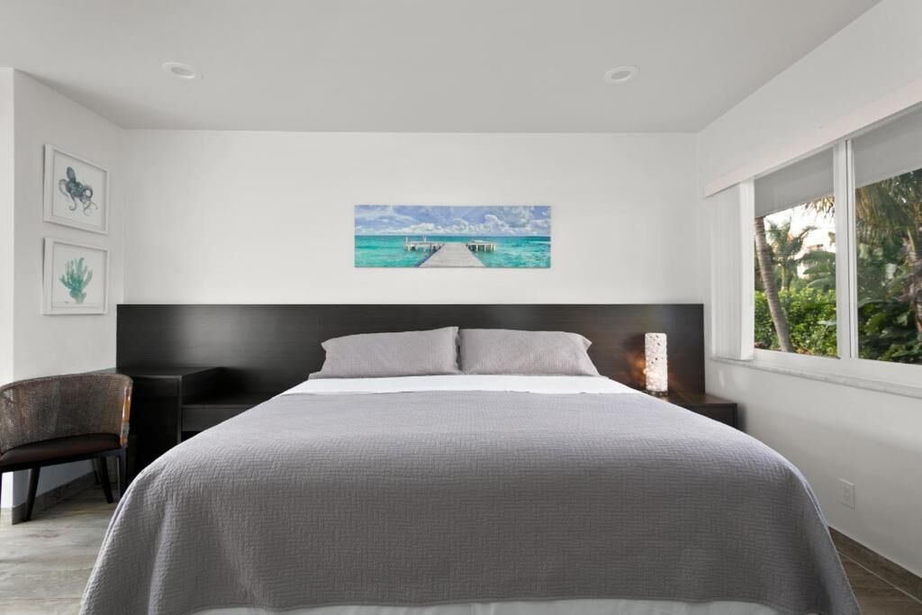 Een moderne slaapkamer met een groot bed, een bureau en een stoel. Op de muur hangt een schilderij van een pier.