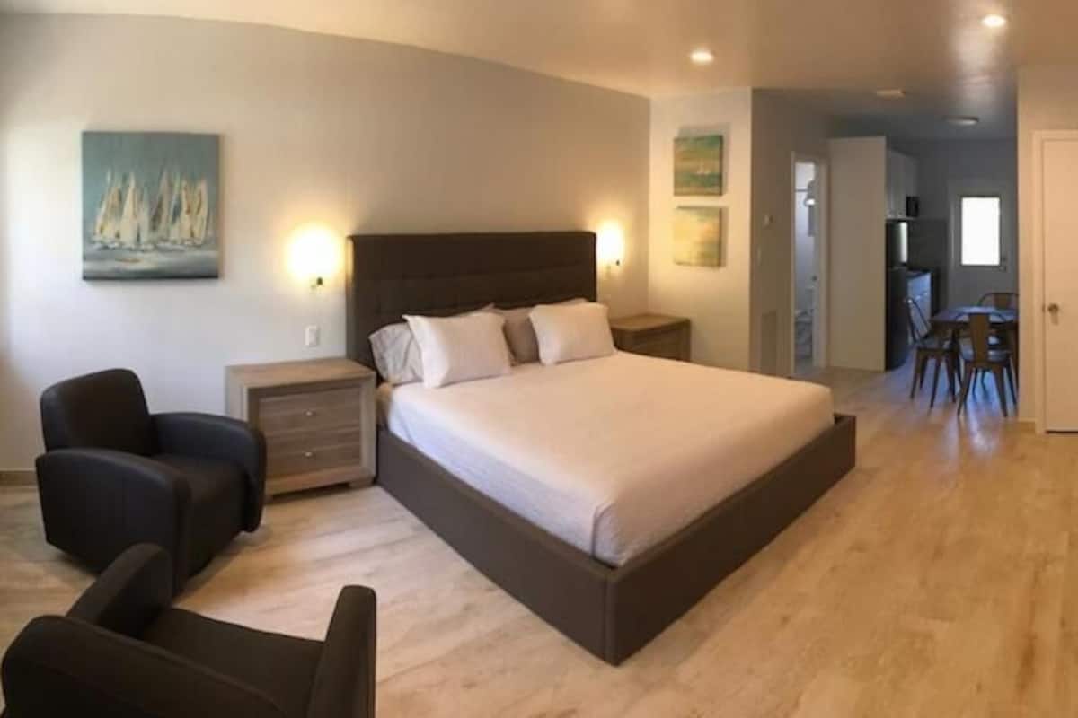 A bedroom with a large bed, bedside tables, a chair, and artwork on the walls.