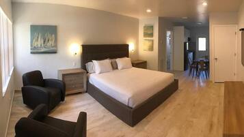 A bedroom with a large bed, bedside tables, a chair, and artwork on the walls.