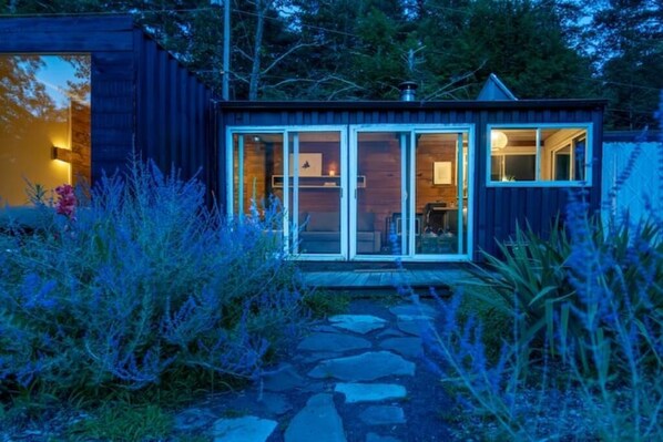 A modern cabin with a stone pathway leading to a glass door entrance. - Container Cabin in the Catskills (Field) (Saugerties)
