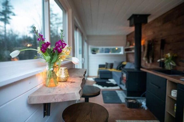 A modern kitchen with a wooden countertop, a vase with flowers, and a view of the outdoors. - Container Cabin in the Catskills (Field) (Saugerties)