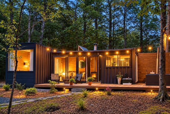 A cabin with a deck, a fireplace, and string lights. - Field Cabin + Mountain Views + Hot Tub + Sauna (Saugerties)