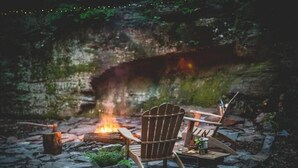 A cozy outdoor seating area with a fire pit, a wooden chair, and a table with a drink.