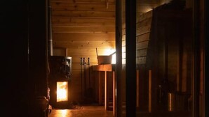 A wooden interior with a central light source, wooden beams on the ceiling, and a visible door frame.