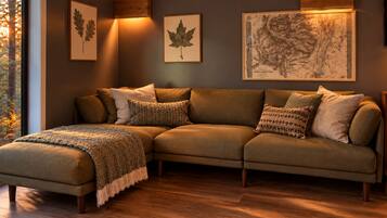 A sectional sofa with a throw blanket, framed botanical prints, and a map on the wall.