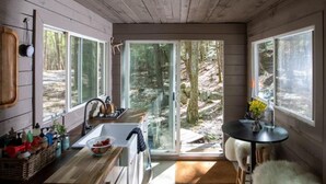 A modern kitchen with a large window, wooden cabinets, and a rustic ceiling.