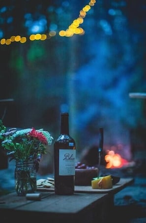 Eine Weinflasche, ein Glas und ein Blumenarrangement auf einem Tisch, Hintergrund unscharf.