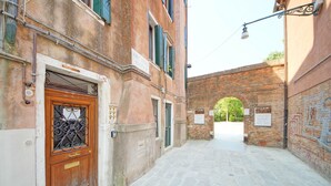 A narrow cobblestone street with a wooden door and a brick archway. - DolceVita Apartments N. 491 (Venice)