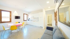 A modern apartment with a dining area, kitchenette, and a living room with a sofa. - DolceVita Apartments N. 491 (Venice)