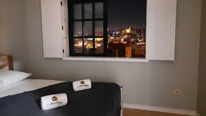 A bedroom with a bed, a window with white shutters, and towels with a logo. - Myriverplace N.6 - PORTO Riverfront Apartment With Breathtaking Views (Vila Nova de Gaia)