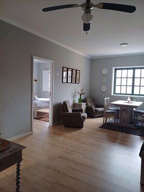Relax in this spacious living room with a dining area, ceiling fan, and large window.