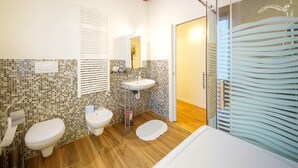 Een badkamer met twee toiletten, een wastafel en een douchehoek.