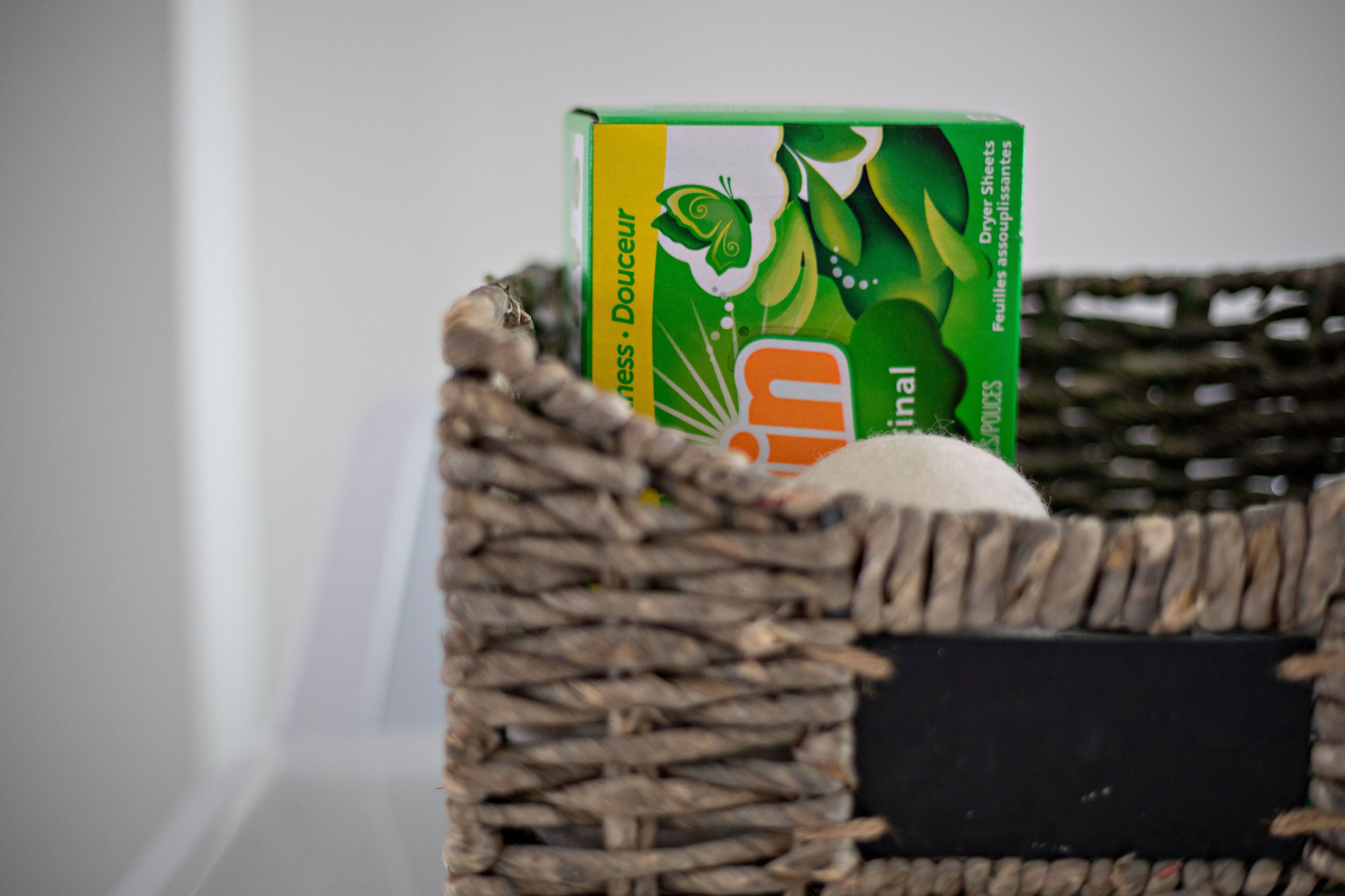 A woven basket containing a green box and a white object.