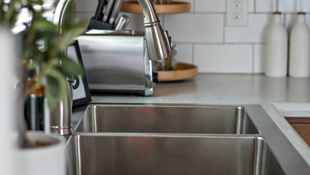Een moderne keuken met roestvrijstalen apparatuur, houten kastjes en een witte tegelachterwand.